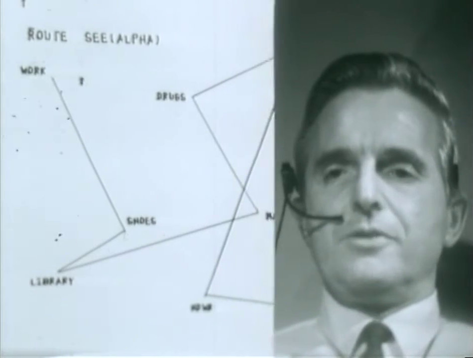 A split-screen showing Doug Engelbart performing The Mother of All Demos; a route map is on the monitor part of the screen.
